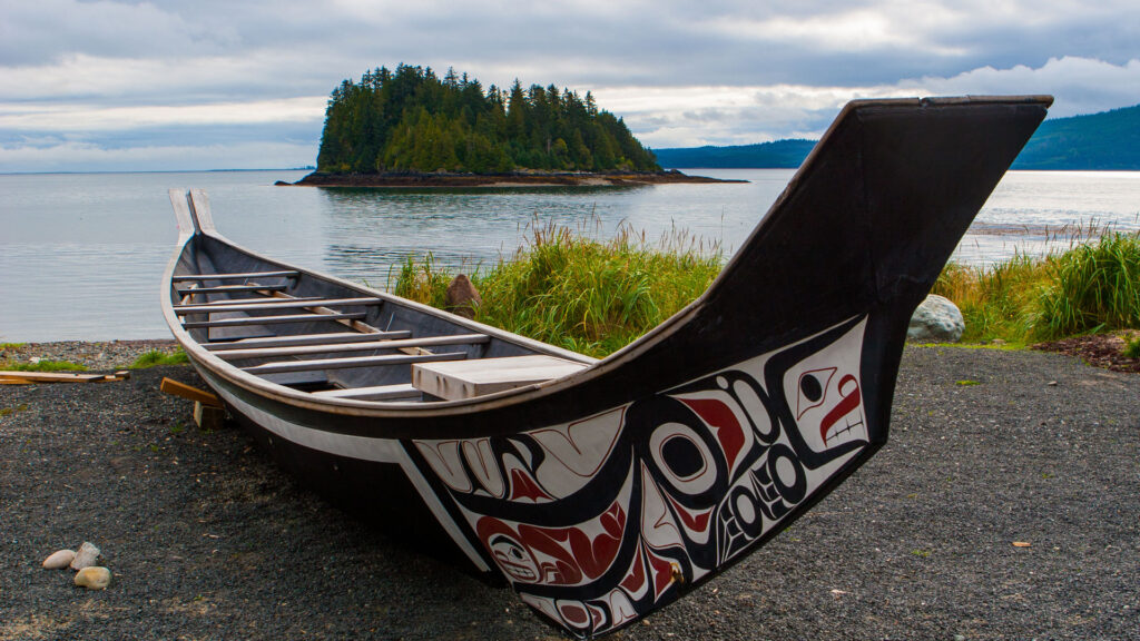Handmade Indigenous boat sitting on the side of a lake.