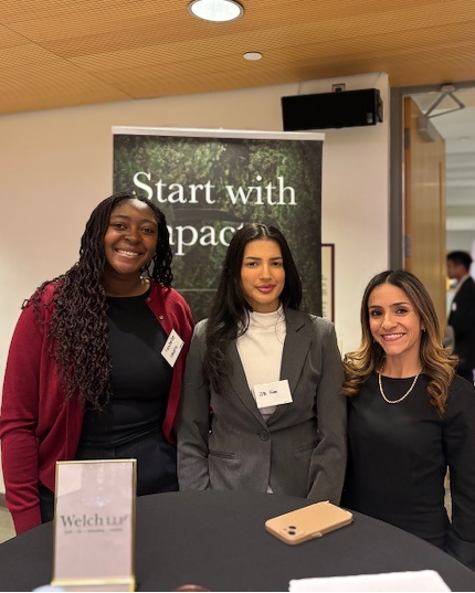 Three women standing in front of a Welch LLP banner smiling at the camera.